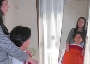 カラー分析中の画像。鏡の前で、クライアントの胸元に二種類の布をかけて比べている